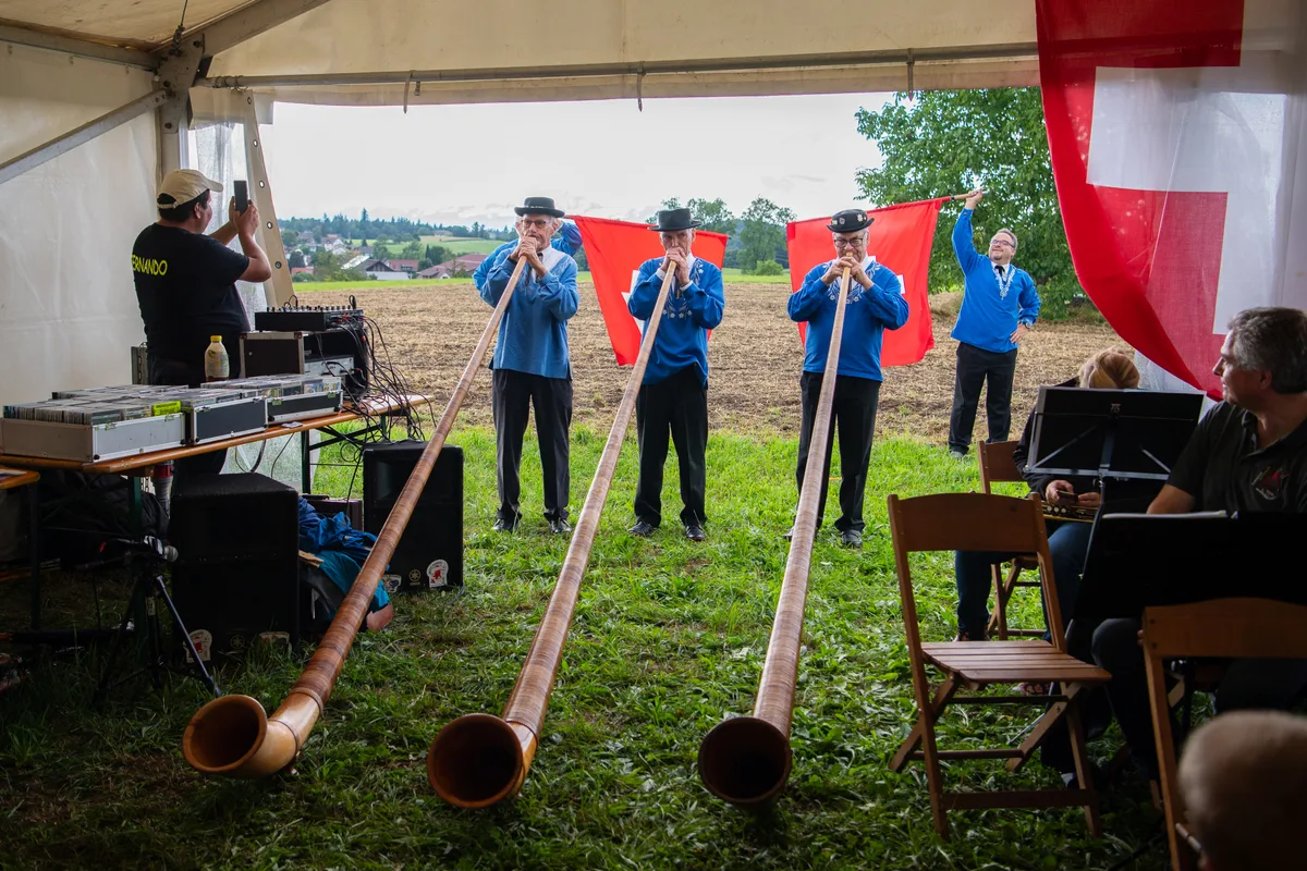 Drei Alphornbläser und zwei Fahnenschwinger am Festzeltende.